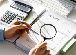 Photo of man reviewing invoice with magnifying glass